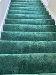 A clean, vibrant green carpeted staircase, showcasing the professional results of JDog Carpet Cleaning & Floor Care Alpharetta in Roswell, GA.