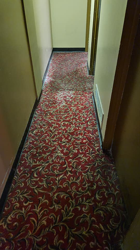 A freshly cleaned red patterned carpet in a long hallway after service by Quality Carpet Cleaning in Lewiston, ID.