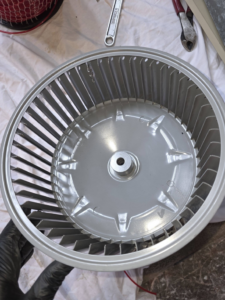 A technician holding a freshly cleaned HVAC blower wheel for Affordable Quality Air Duct Cleaning in Denver, CO