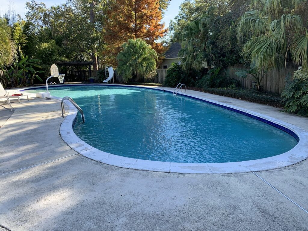 A beautifully clean, blue kidney-shaped pool, maintained by Pool King in Southhold, NY.