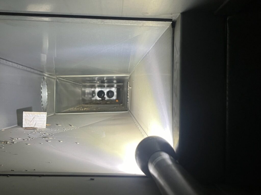 A view inside a clean metal air duct illuminated by a flashlight, showing the results of Vacman Air Duct Cleaning in South Bend, IN