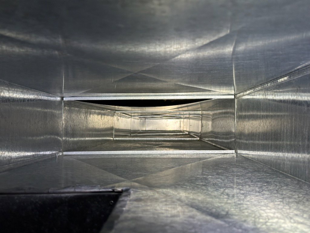 An angled view inside a clean metal air duct, demonstrating the quality work of Vacman Air Duct Cleaning in South Bend, IN