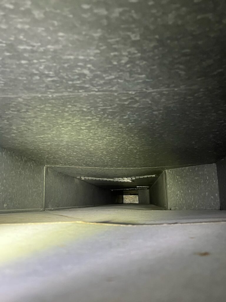 A bright view inside a clean metal air duct, showcasing the quality work of Vacman Air Duct Cleaning in South Bend, IN