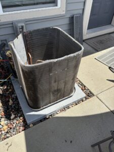 Clean coils of an outdoor air conditioning unit with the side panel removed, indicating recent service or inspection by Holzer Heating And Cooling in Savage, MN