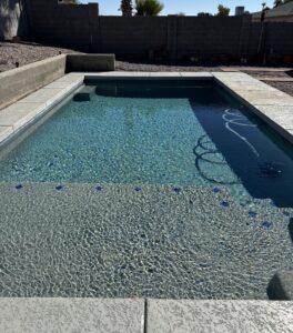 A clean swimming pool with an automatic pool cleaner hose visible, maintained by Pool Pals in Franklin, MA.