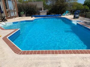 A sparkling clean swimming pool with professional cleaning equipment nearby, by Pool Maid Pro in Decatur, AL.