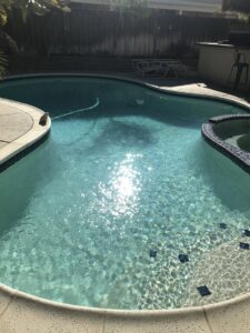 A sparkling clean pool with a visible pool vacuum hose, indicating recent or ongoing cleaning by Good Guy Pool Service in Moreno Valley, CA.