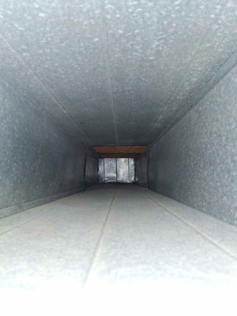 An interior view of a clean rectangular metal air duct, representing quality HVAC work by DUCTZ of Siouxland in Vermillion, SD.