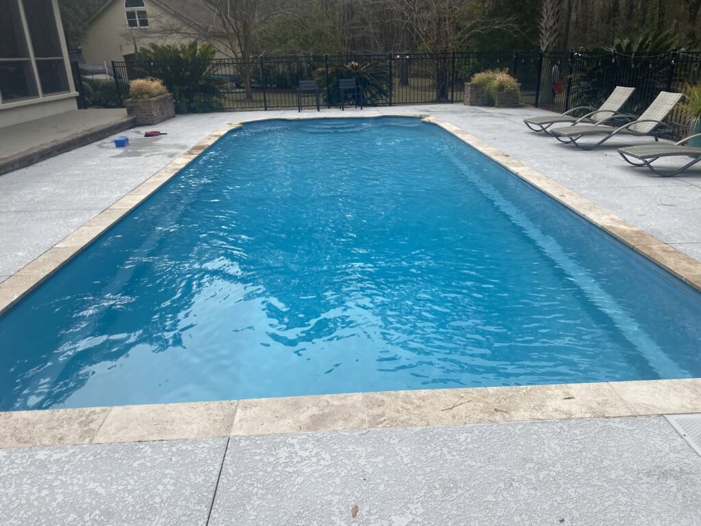 A clean rectangular swimming pool with elegant stone coping, showcasing the meticulous service of Pool King in Summerville, SC.