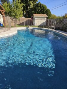A clean residential pool with a vacuum hose in the water, maintained by Vanguard Pool Care in Phoenix, AZ