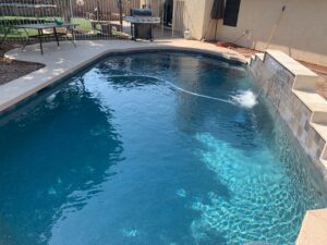 A clean residential swimming pool featuring a decorative waterfall, maintained by East Mesa Pools, LLC in Mesa, AZ.