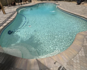 A sparkling clean swimming pool with a robotic cleaner visible, showcasing the quality service of Brigade Pool Services in Tempe, AZ.