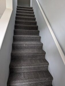 A freshly cleaned carpeted staircase with visible lines after service by Tampa Steam Team in Plant City, FL.