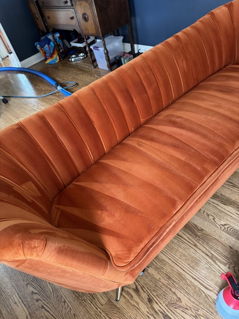 A beautifully cleaned orange velvet sofa showing fresh cleaning lines by 5 Alarm Carpet Care in West Allis, WI.