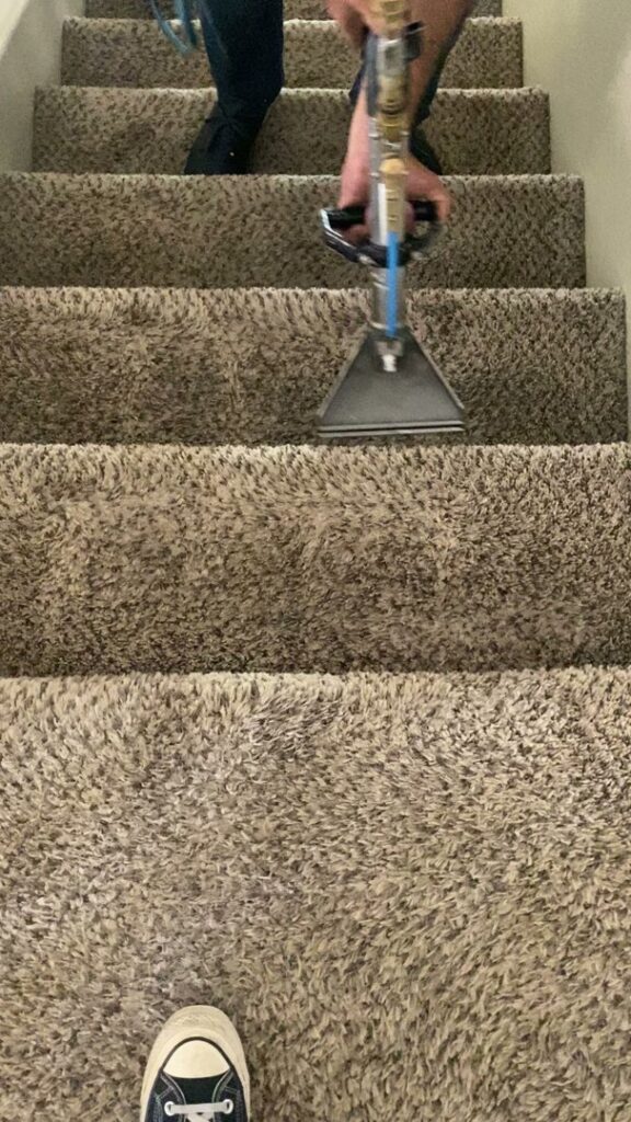 A professional cleaning technician from Raysco, Inc. cleaning carpeted stairs with a specialized wand in Las Vegas, NV.