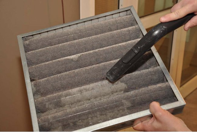 Hands cleaning a dirty HVAC air filter, a service provided by Controlled Climate Solutions in Decatur, AL.
