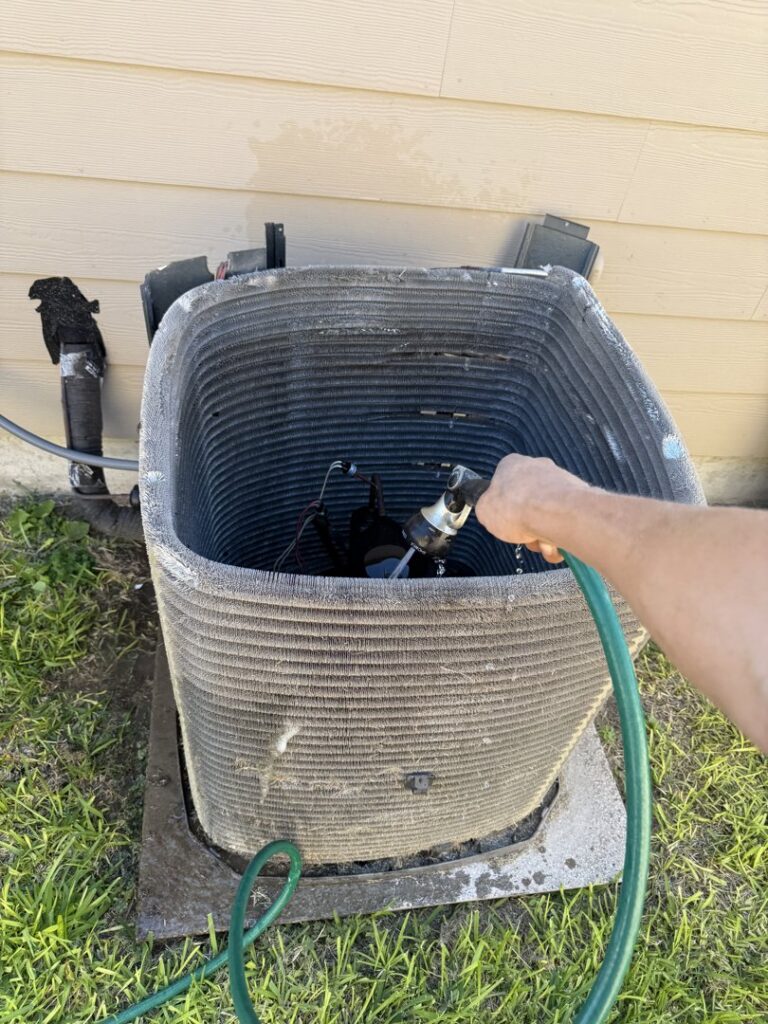 A technician cleaning the coils of an outdoor AC condenser unit for Gibson's Air Conditioning & Heating in Corpus Christi, TX.