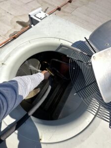 A technician cleaning the outdoor HVAC condenser coils for Rogue Mechanical in Las Vegas, NV.