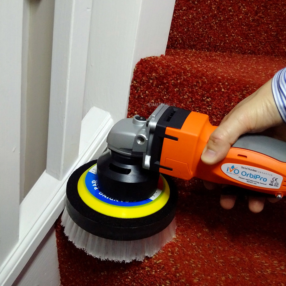 A professional cleaning a red carpeted staircase with a rotary brush tool for Johns Creek Carpet Cleaner in Johns Creek, GA.