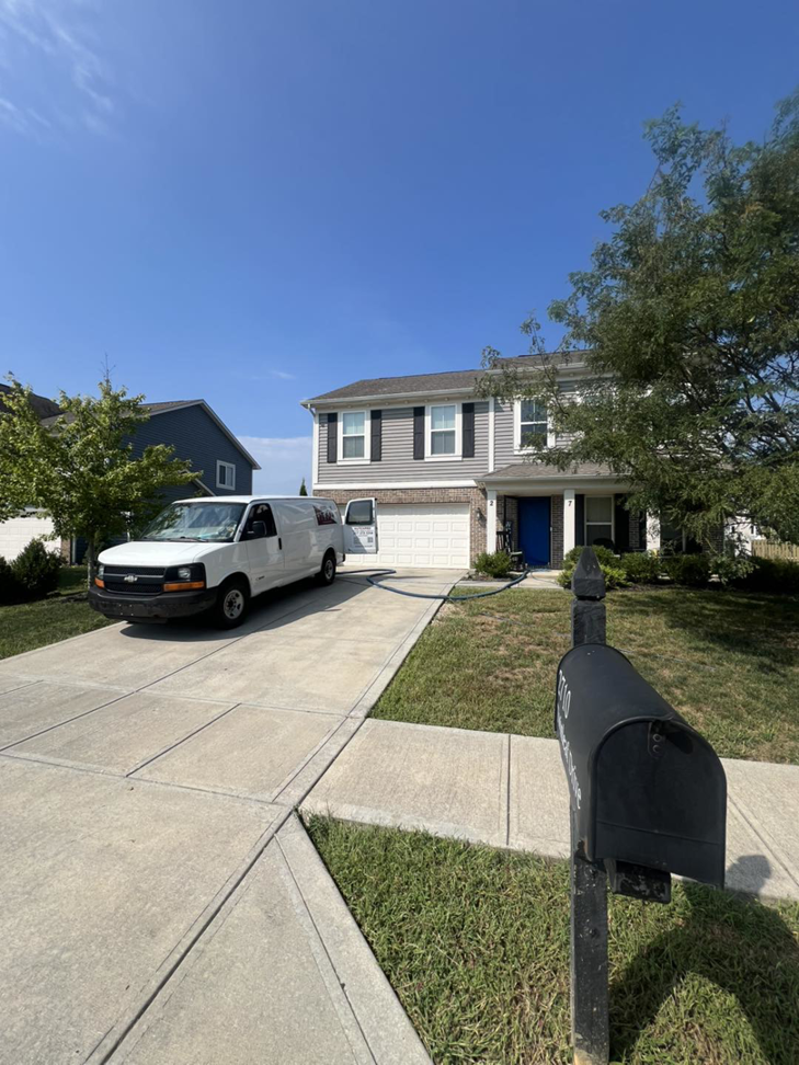 A professional cleaning van with hoses extended to a residential home, indicating a service call by HutchPro Carpet Cleaning Plus in Indianapolis, IN.