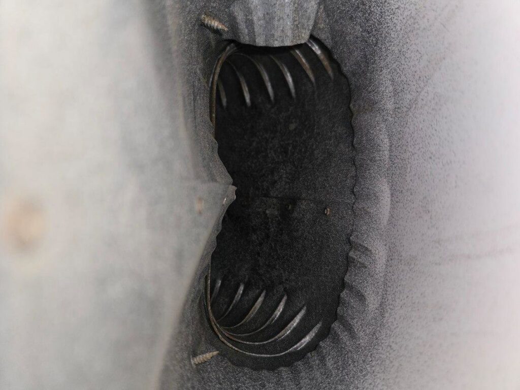 A close-up view of a clogged dryer vent opening with lint and debris, indicating dryer vent cleaning services by Pro Power Air Duct & Dryer Vent Cleaning in Kenosha, WI.