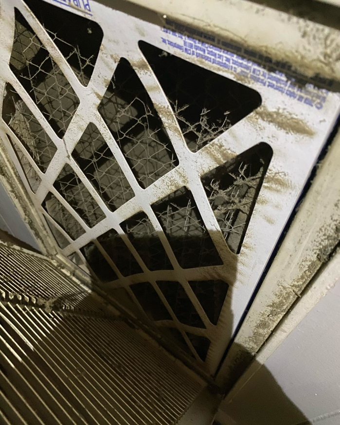 A severely clogged HVAC air filter visible in a return vent, serviced by B & H Heating and Air Services LLC in Local City, ST.