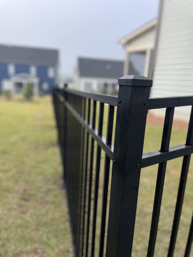 A close-up view of a black aluminum fence post and panels, highlighting detail by RDU Fence in Holly Springs, NC.