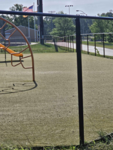 A close-up view of a black chain-link fence post and fence line near a playground, installed by Atchison Fence in Effingham, KS.