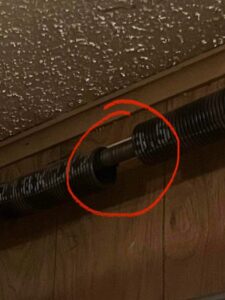 A close-up view of a broken garage door spring, highlighted for repair by Rhino Garage Doors LLC OKC in Edmond, OK.