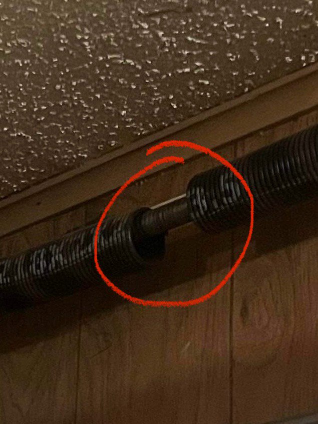 A close-up view of a broken garage door spring, highlighted for repair by Rhino Garage Doors LLC OKC in Edmond, OK.