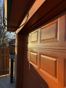 A close-up view of a textured brown panel garage door installed by Colorado Garage Door Guy in Aurora, CO.