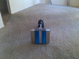 A close-up of a professional carpet cleaning machine with blue brushes on a carpet by Steamex Carpet Cleaning Phoenix, AZ.