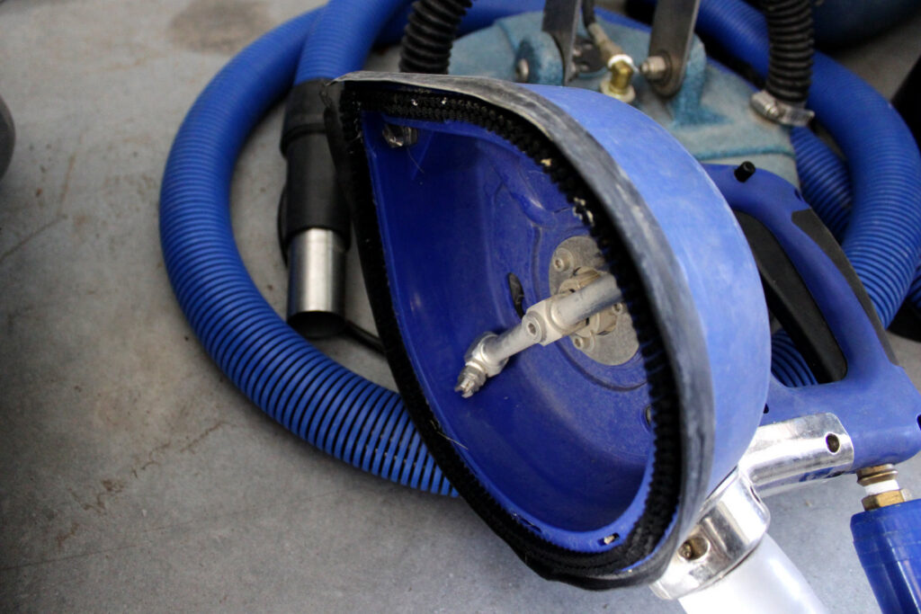 Close-up of a professional carpet cleaning wand tool and blue hoses used by Christenson Cleaning & Restoration in Hastings, NE.