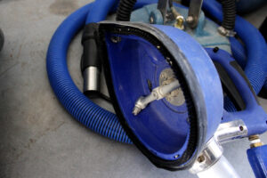 Close-up of a professional carpet cleaning wand tool and blue hoses used by Christenson Cleaning & Restoration in Hastings, NE.