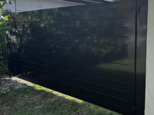 A close-up view of a dark grey horizontal slat gate, part of a fence installation by HD Multi Service USA INC in Miami, FL.
