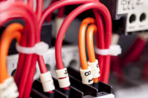 A close-up view of neatly connected red and orange electrical wires within a panel by OMR Electrical Contractors Inc. in Cape Coral, FL.