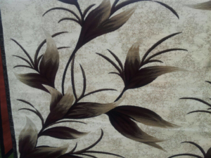 A close-up view of a decorative rug featuring a brown floral pattern from Sunshine Rugs and Art in Londonderry, NH.