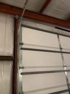 A close-up of a garage door track and roller mechanism, showing repair or installation by Affordable Overhead Garage Door in Modesto, CA