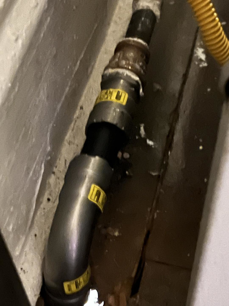 A close-up view of a gas piping connection with yellow warning labels, demonstrating work by Basurto's Heating & Cooling in Milwaukee, WI.