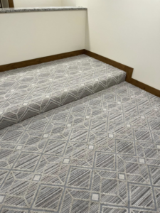 Close-up of geometric pattern carpet professionally installed on stairs by Flooring Liquidator in Orem, UT.