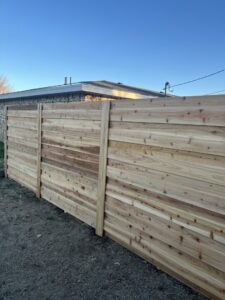 A close-up view of a new horizontal slat wooden fence, showcasing quality craftsmanship by DC Fencing LLC in Clovis, NM.