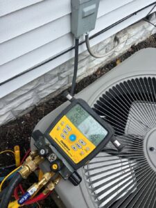 Close-up of HVAC gauges connected to an outdoor AC unit during diagnostic service by Allegiance Heating & Air in Greenville, IN.