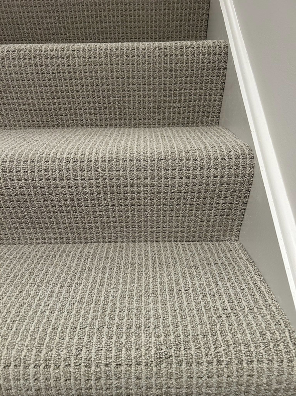 Close-up view of a freshly installed patterned carpet on a residential staircase by Creative Carpet Solutions LLC in Houston, TX.