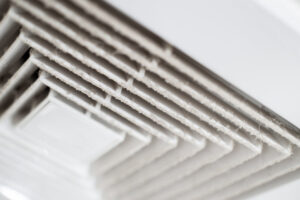A close-up view of a dirty ceiling air vent showing significant dust accumulation, ready for cleaning by Air Doctor Duct Cleaning & Lining in Tulsa, OK.