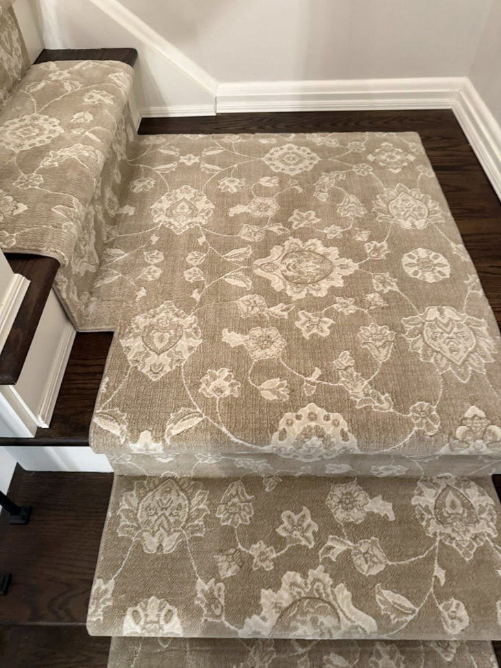 A close-up view of a patterned carpet runner expertly installed on a staircase landing by Garrard's Flooring Service LLC in Cleveland, OH.