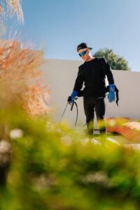 A close-up of a pest control technician from Aloe Pest Control spraying a perimeter in Mesa, AZ.