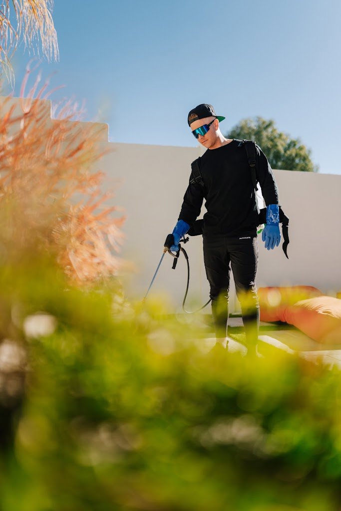 A close-up of a pest control technician from Aloe Pest Control spraying a perimeter in Mesa, AZ.