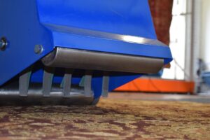 Close-up of a rug duster machine removing dirt from an oriental rug at Oriental Rug Cleaning Facility in Tampa, FL