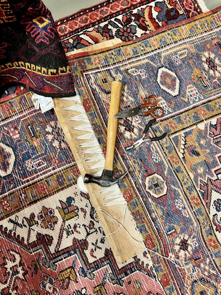 Close-up of a detailed rug repair in progress with tools at Bijar Oriental Rugs, a carpet contractor in Atlanta, GA.