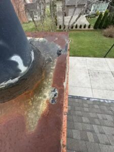 A close-up view of a rusty and worn chimney flue and cap, indicating the need for repair from The Chimney Doctor in Louisville, KY.